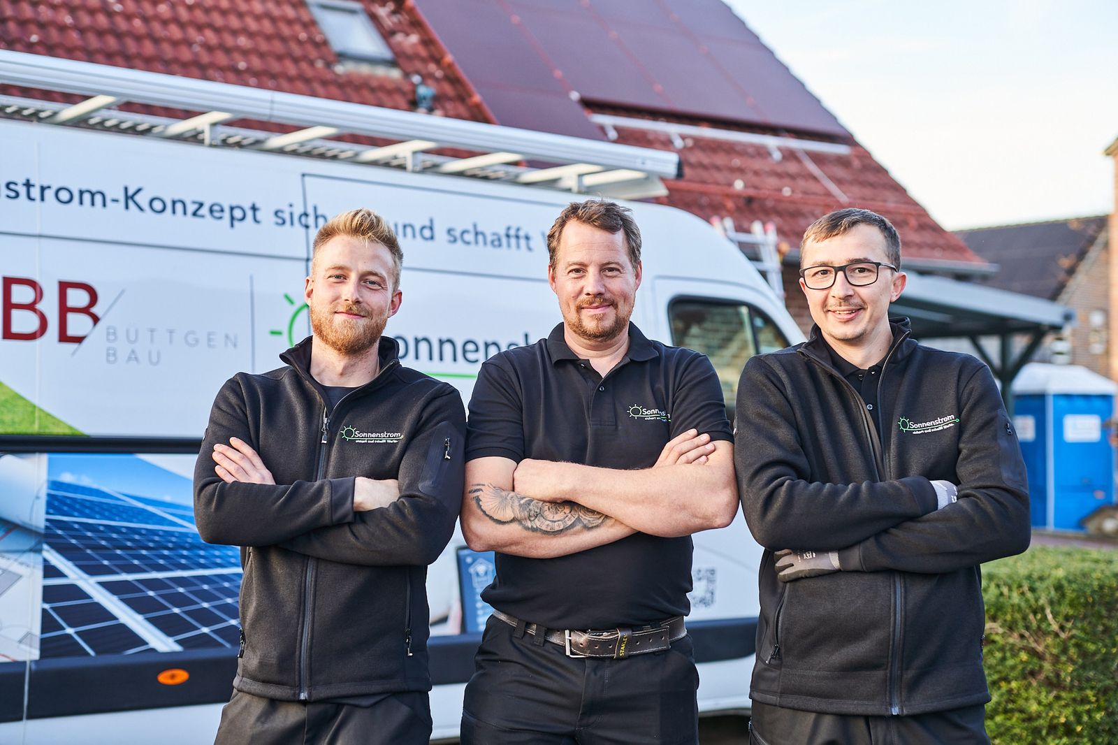 Drei Sonnenstrom-Mitarbeiter vor dem Firmenwagen