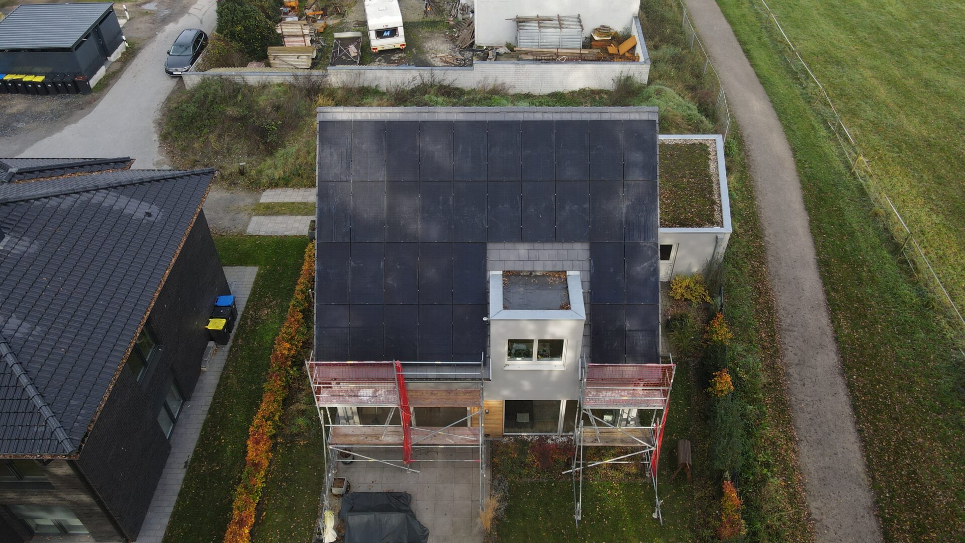 Drohnenbild eines Hauses mit Solar­dach, umgeben von Nachbargebäuden und Grünflächen.